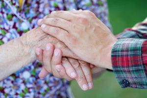 Young male hand holding an elderly woman's hand